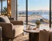 Illustrative airport lounge with comfortable seating, a suitcase and an aircraft beyond the windows